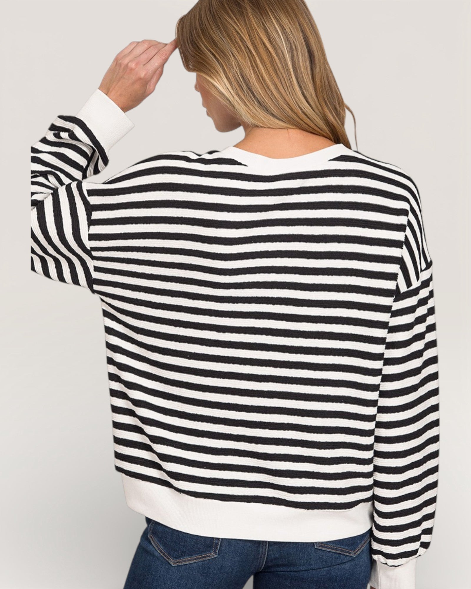 Woman wearing a black and white striped sweater on a plain background