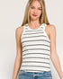 Woman wearing a white tank top with black stripes against a plain background