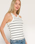 Woman wearing a striped tank top and jeans against a plain background