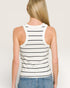 Person wearing a white tank top with black stripes on a plain background