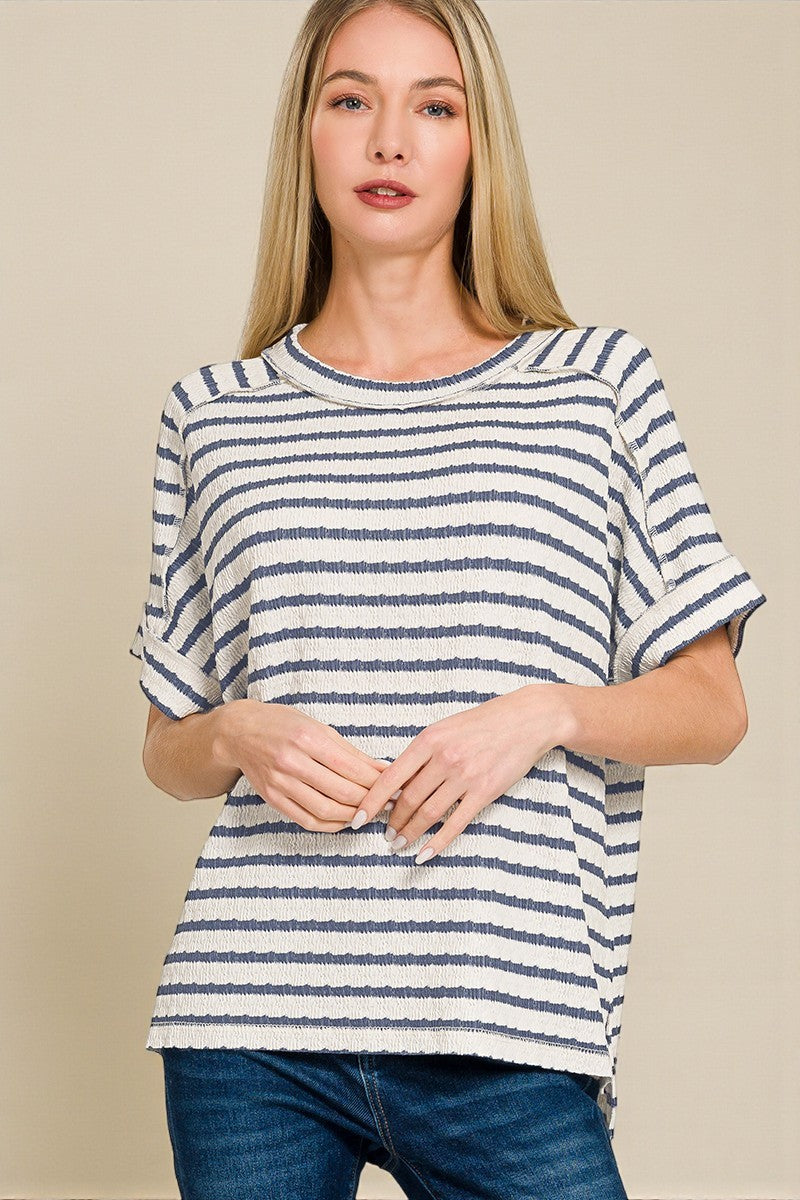 Woman wearing a blue and white striped shirt against a beige background
