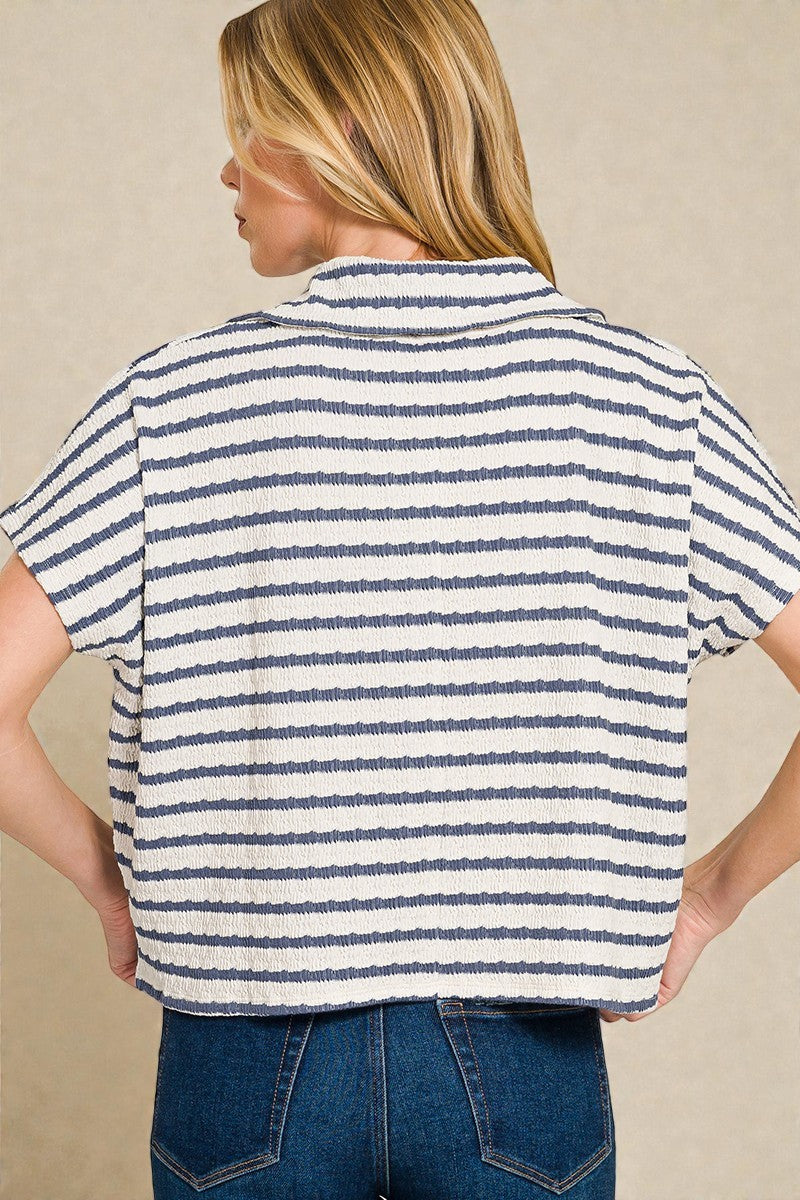 Person wearing a striped shirt and jeans against a beige background