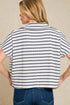 Person wearing a striped shirt and jeans against a beige background