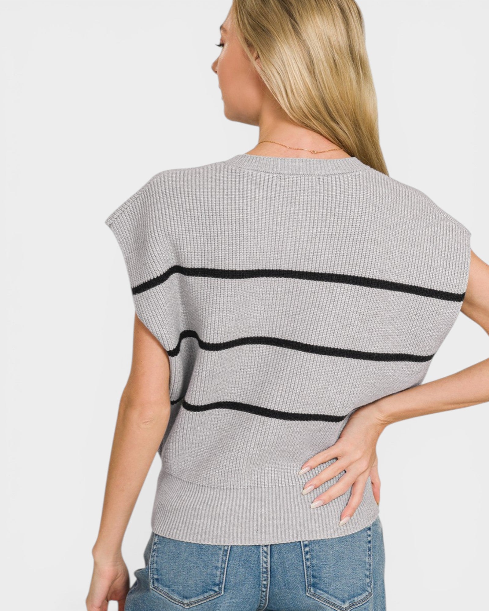 Woman wearing a gray sweater with black stripes on a plain background