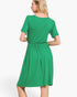 A woman wearing a bright green short-sleeve dress, shown from the back against a plain light gray studio background.