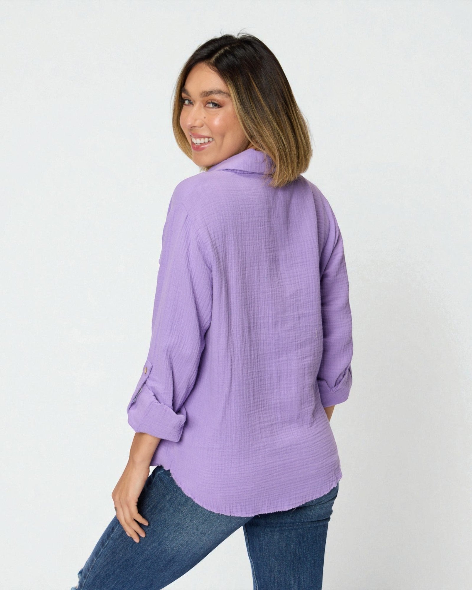 Woman wearing a purple shirt and blue jeans on a white background