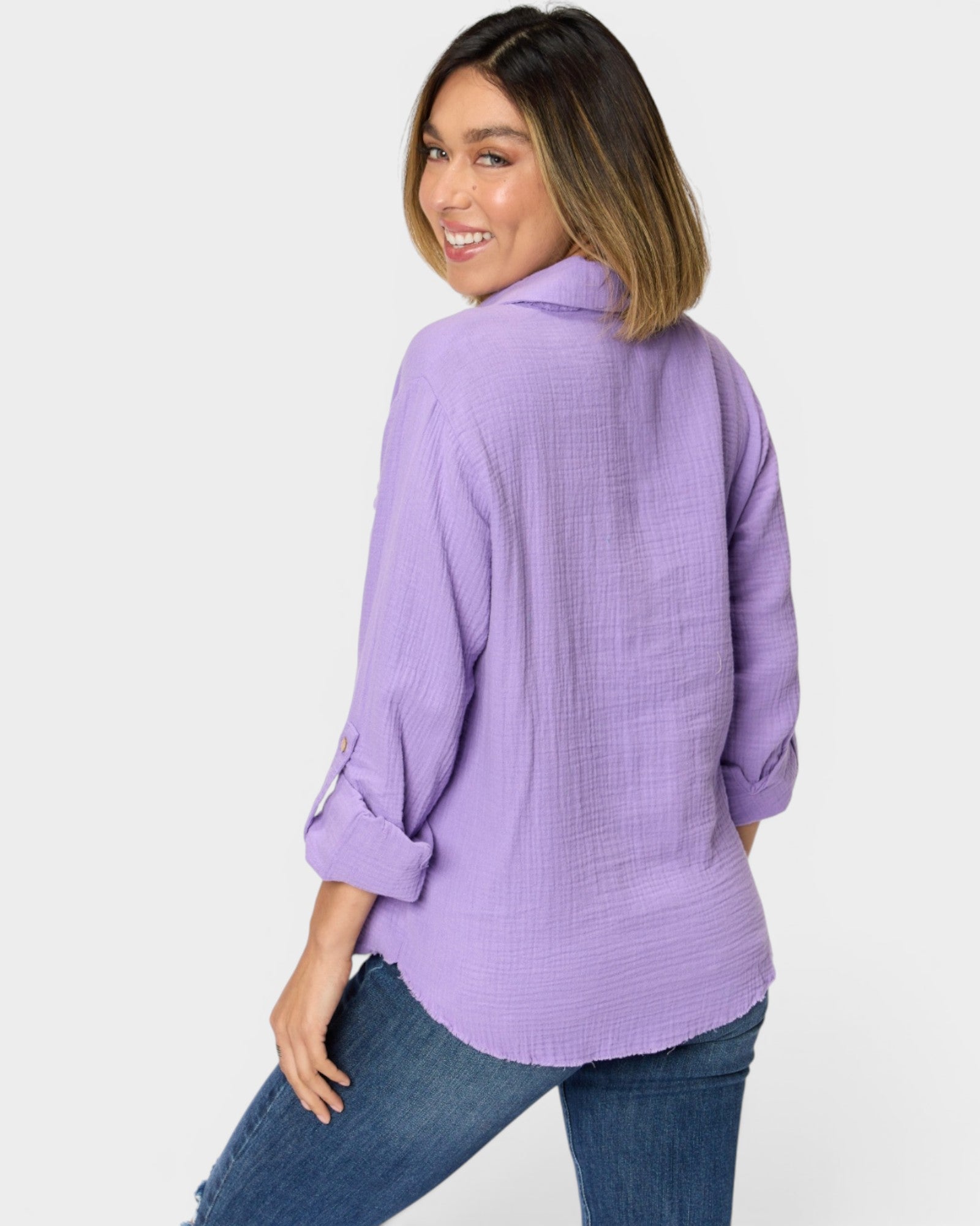 Woman wearing a purple shirt and blue jeans on a white background