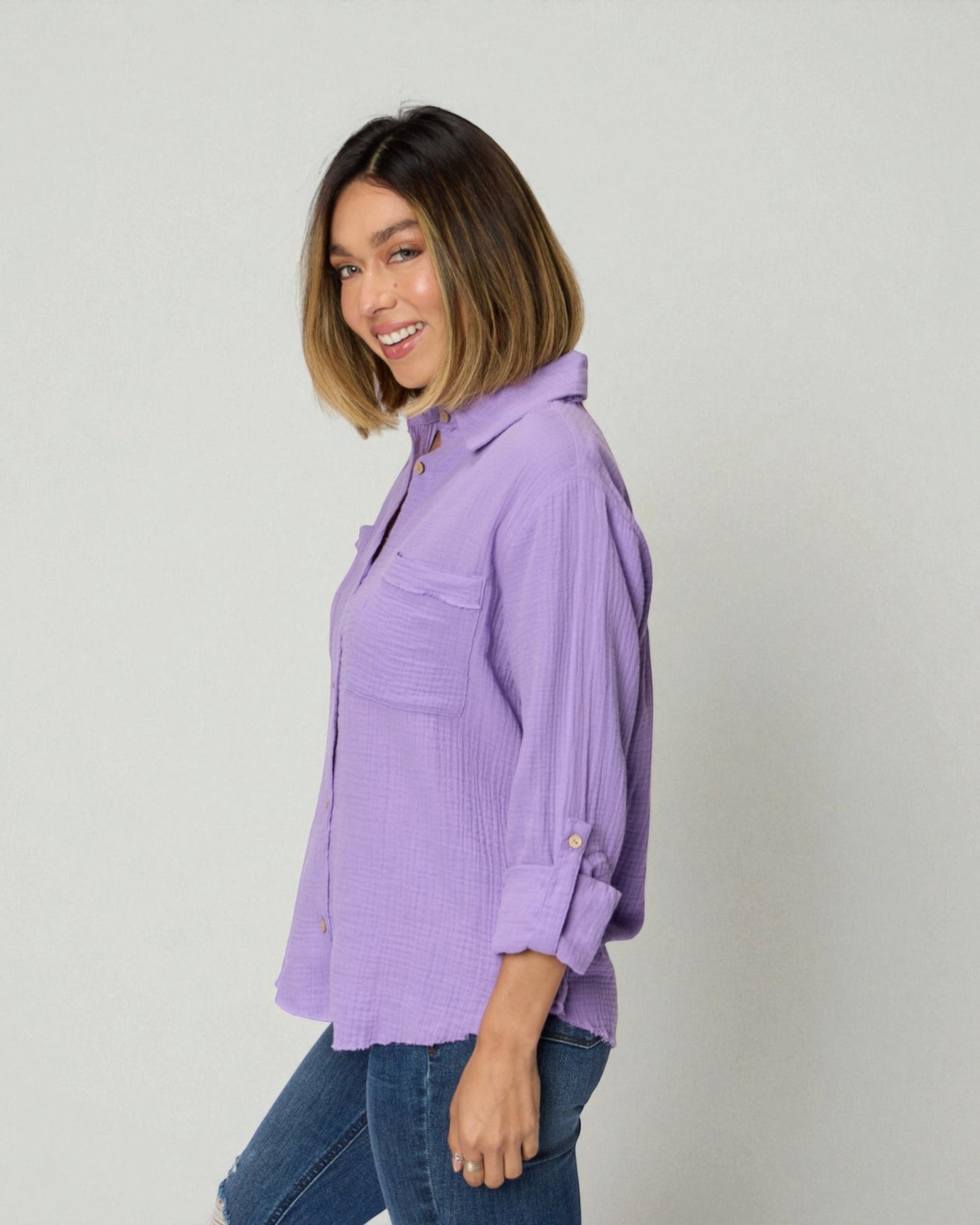 Woman wearing a purple shirt and blue jeans against a plain background