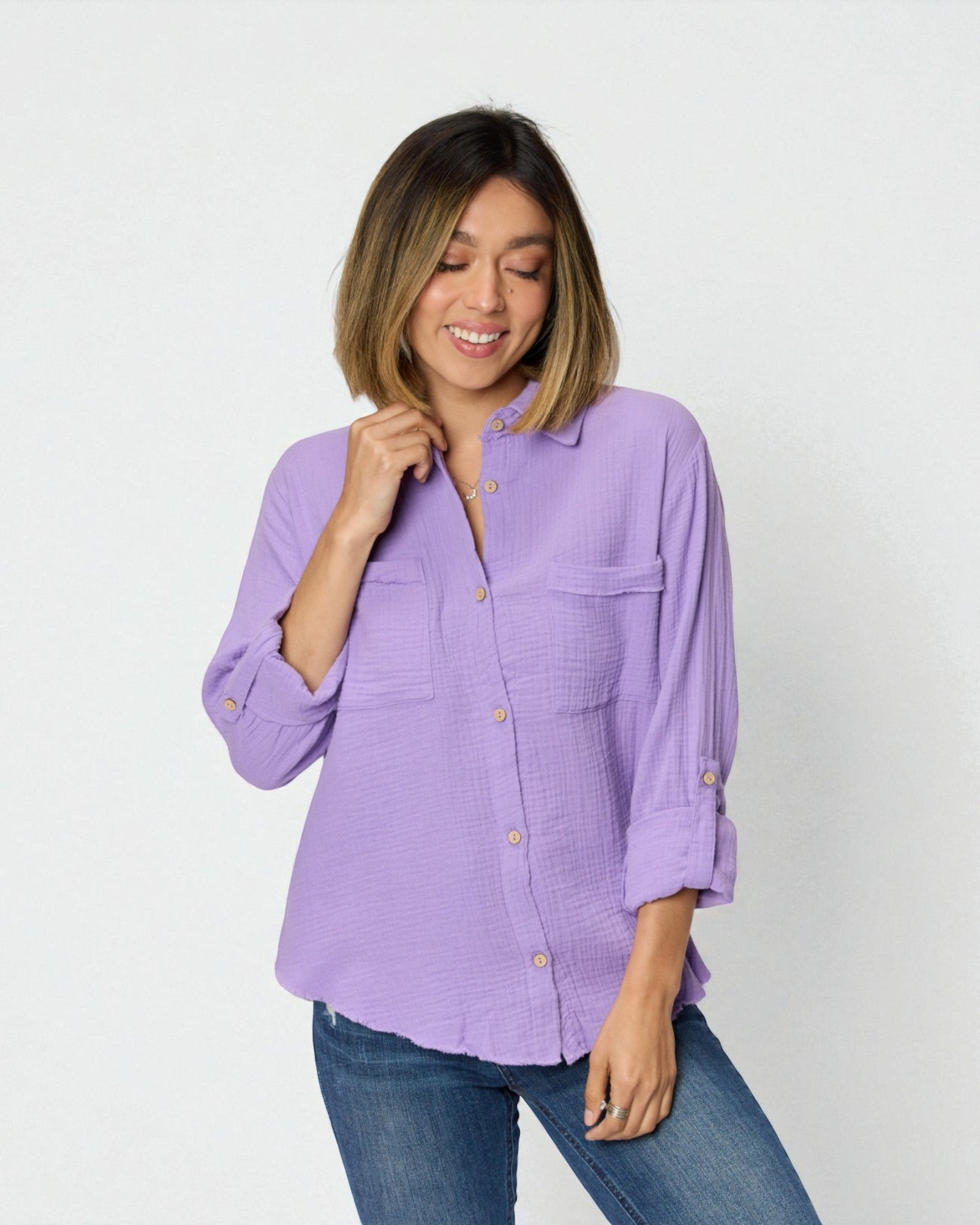 Woman wearing a purple shirt and blue jeans against a white background