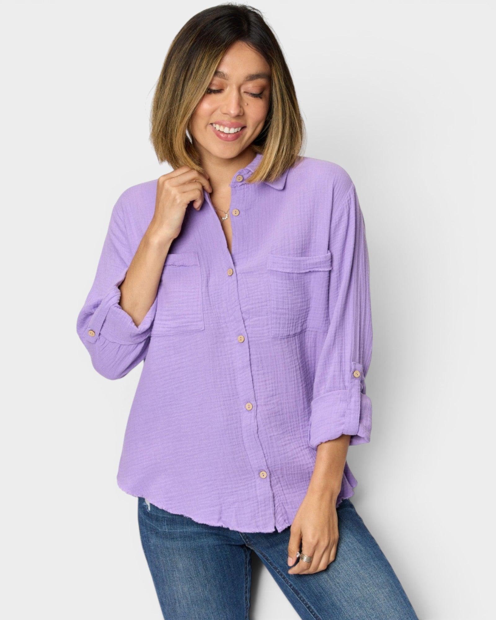 Woman wearing a purple button-up shirt and blue jeans against a white background