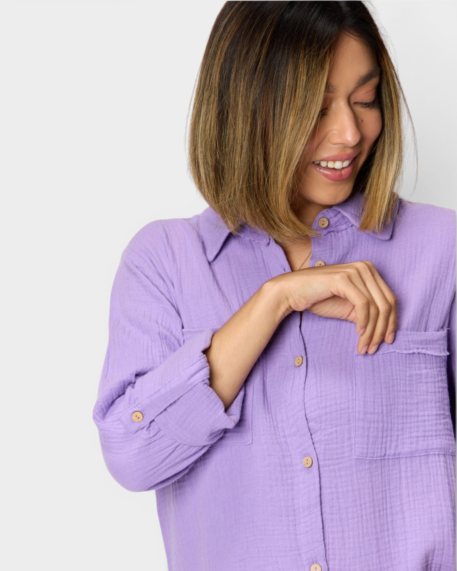 Woman wearing a light purple button-up shirt against a white background