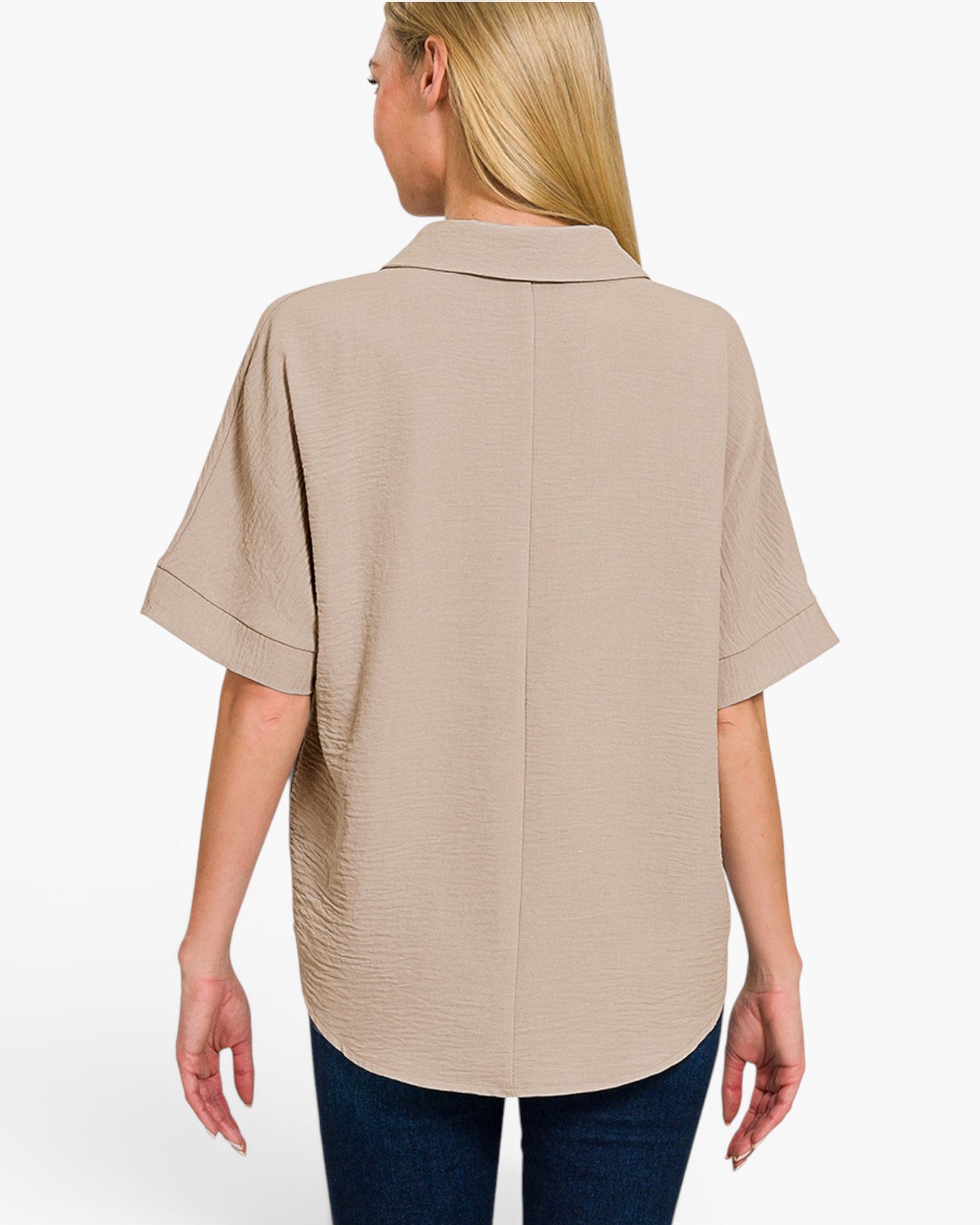 A woman shown from the back wearing a light beige short-sleeve collared blouse with a textured crinkle fabric, paired with dark blue jeans, against a plain white background.
