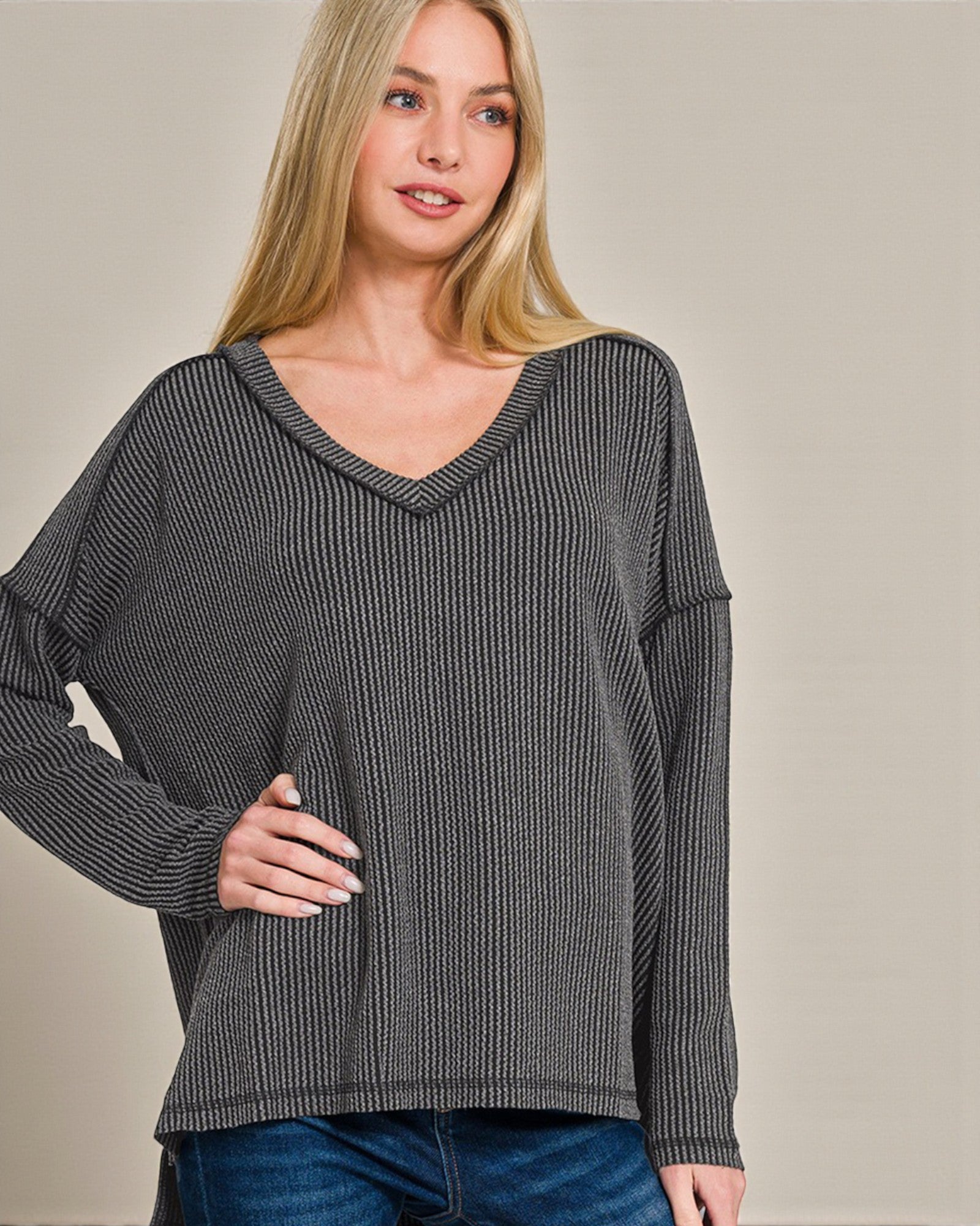 Woman wearing a gray ribbed sweater against a plain background