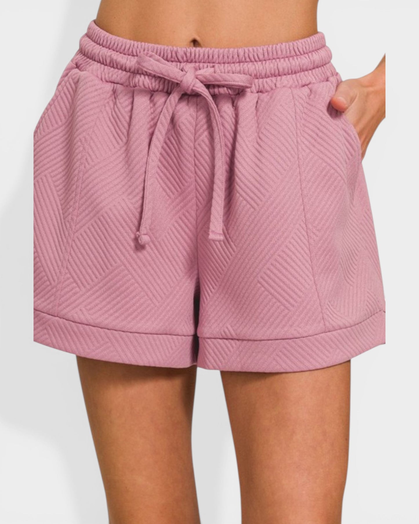 Pink quilted shorts with a drawstring on a white background