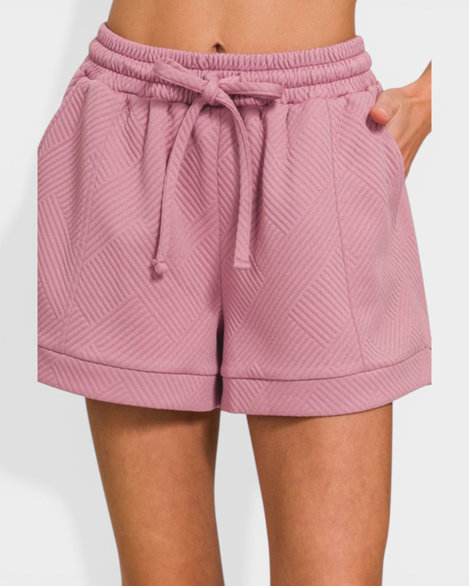 Pink quilted shorts with a drawstring on a white background