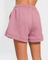Pink shorts with a textured pattern worn by a person on a white background