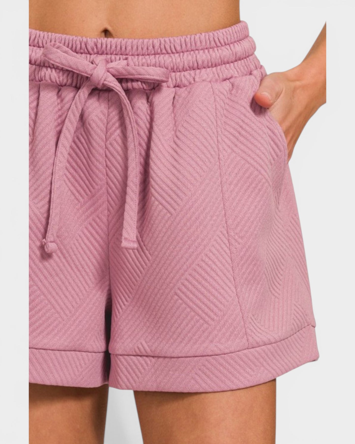 Pink quilted shorts with a drawstring on a white background