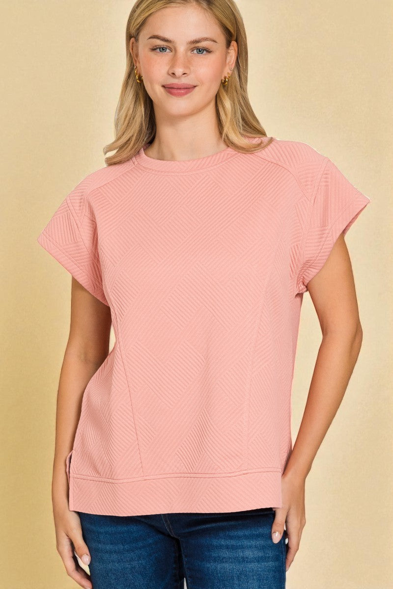 Woman wearing a pink textured top against a beige background