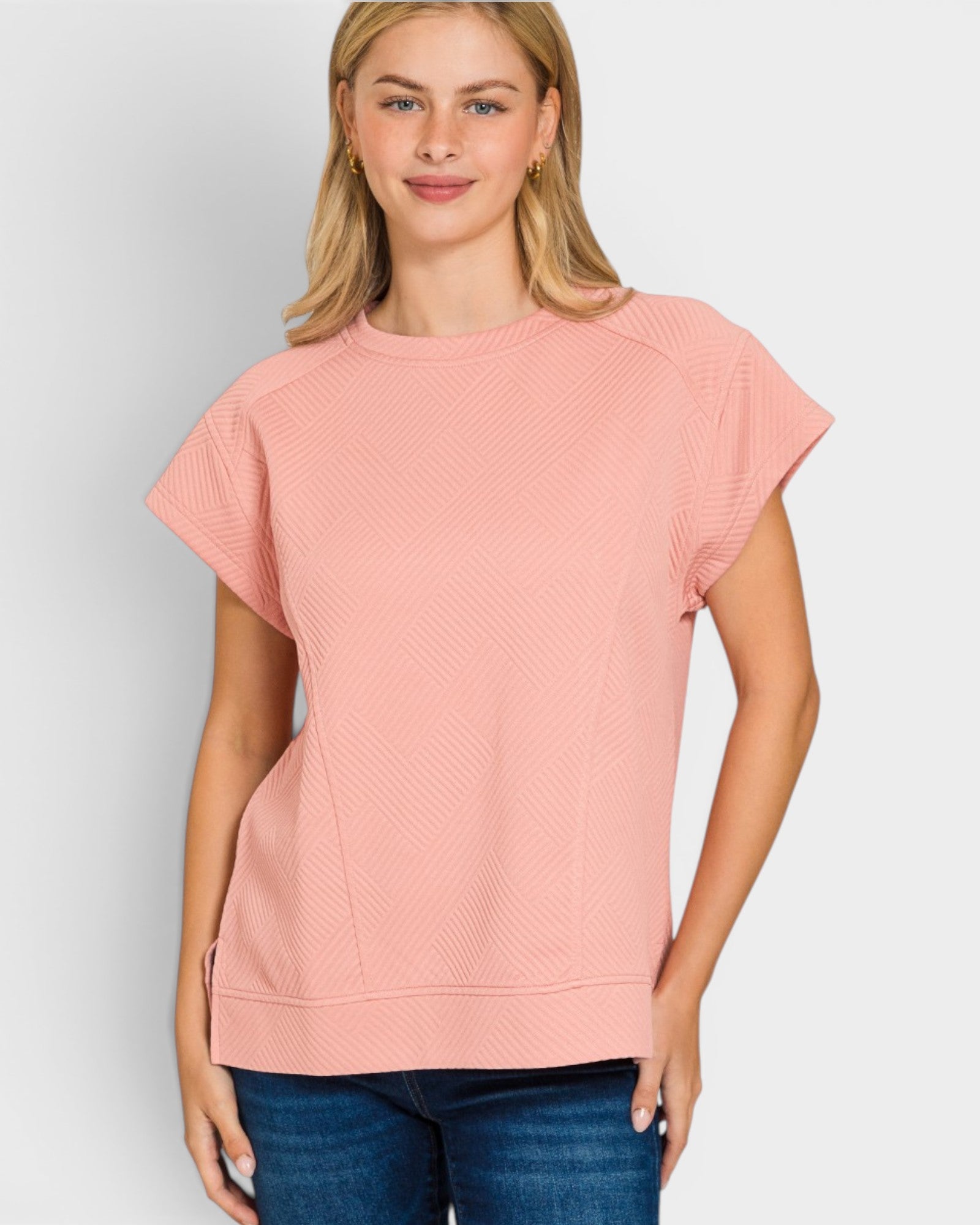 Woman wearing a pink textured top against a light gray background