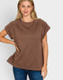 Woman wearing a brown textured top and blue jeans on a white background