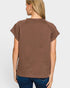 Woman wearing a brown textured top and blue jeans on a white background
