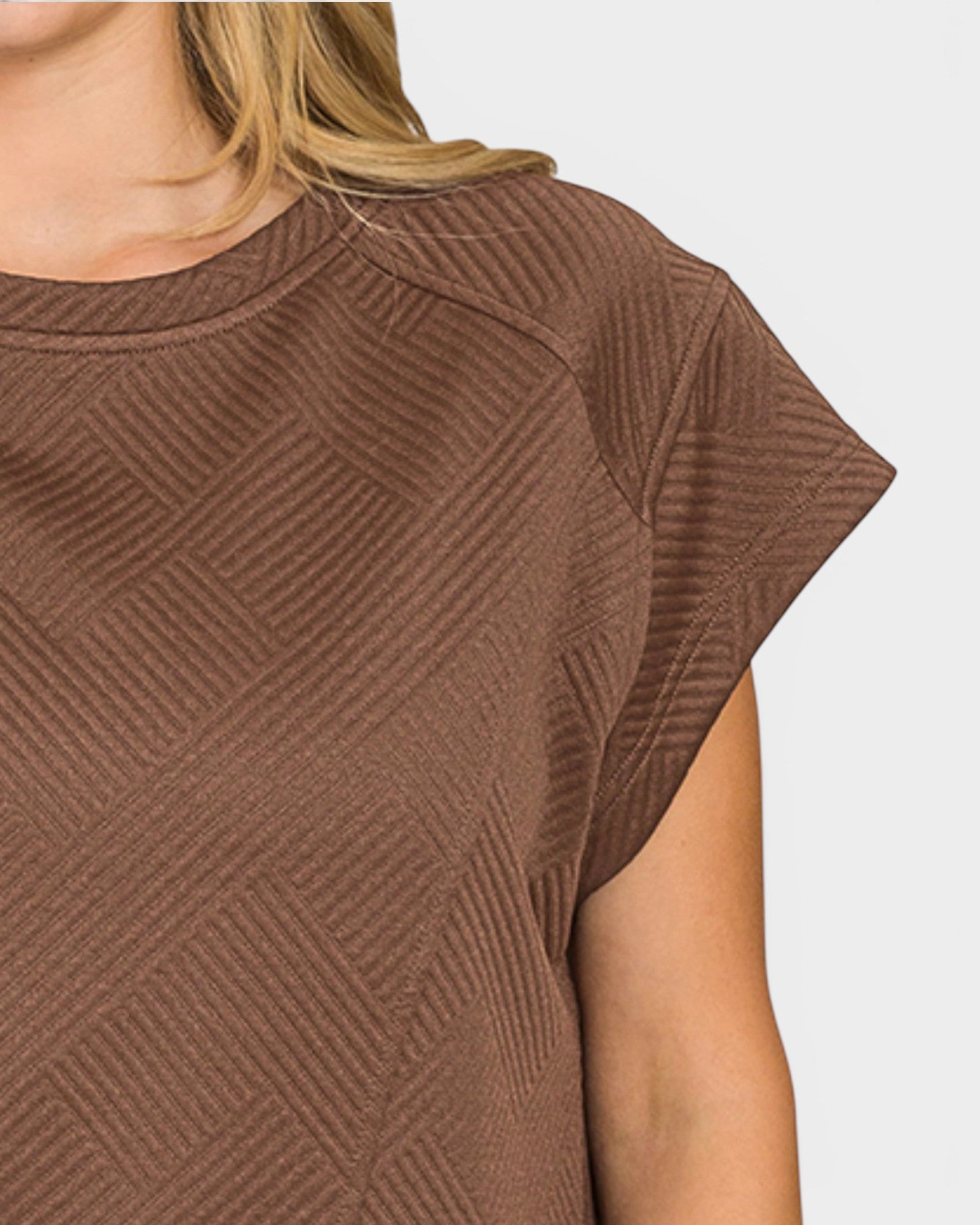 Brown textured short-sleeve top on a person against a white background
