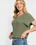 Woman wearing a green ribbed sweater and blue jeans on a white background