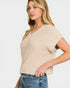 Woman wearing a beige knitted top and blue jeans on a white background