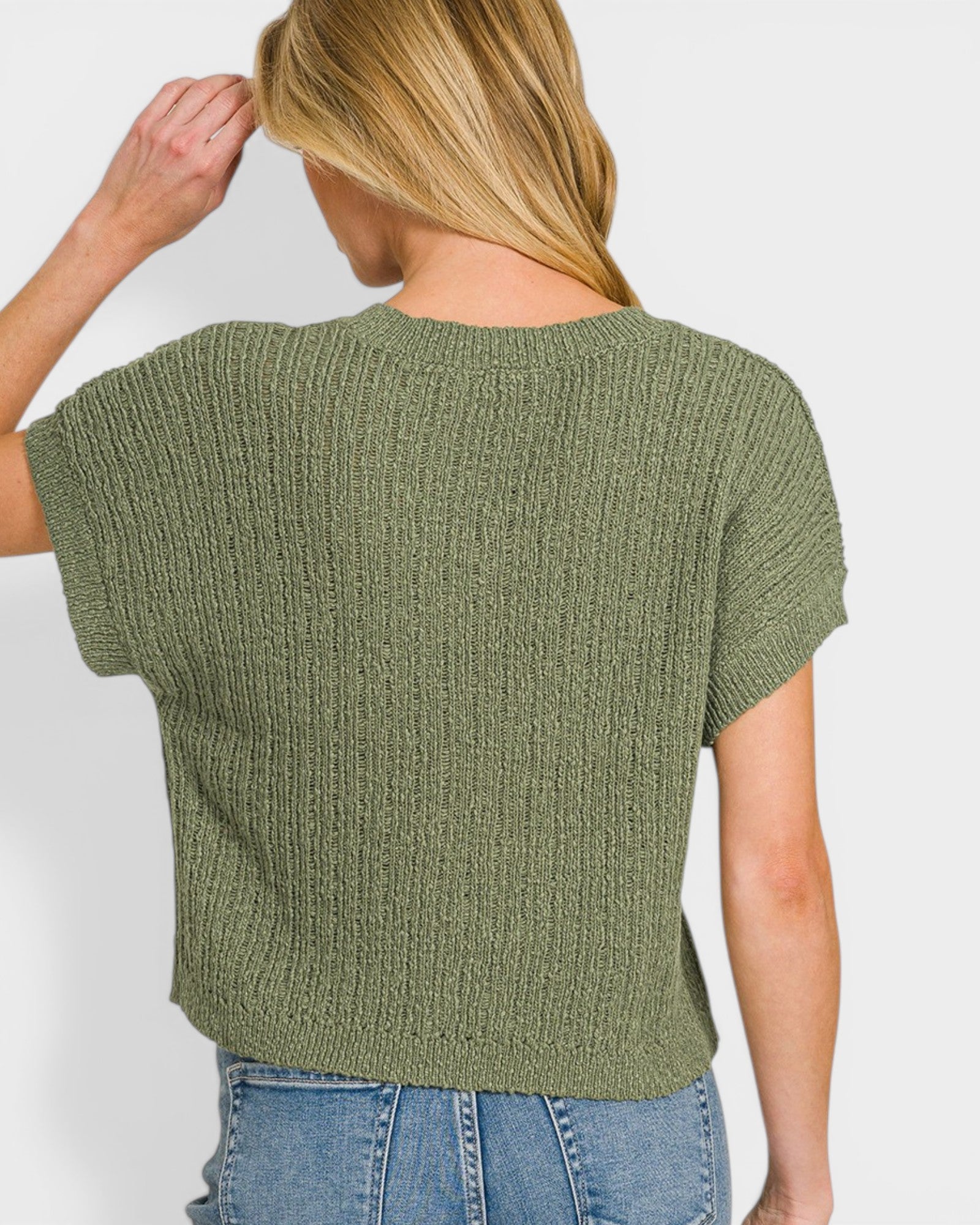 Woman wearing a green knitted top against a plain background