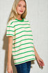 Woman wearing a green and white striped shirt against a light tiled wall.