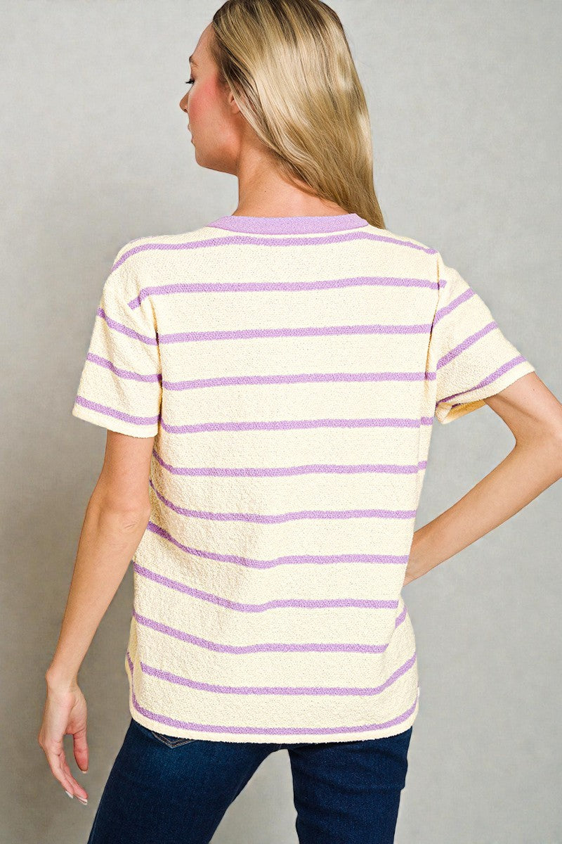 Woman wearing a yellow and purple striped shirt against a gray background