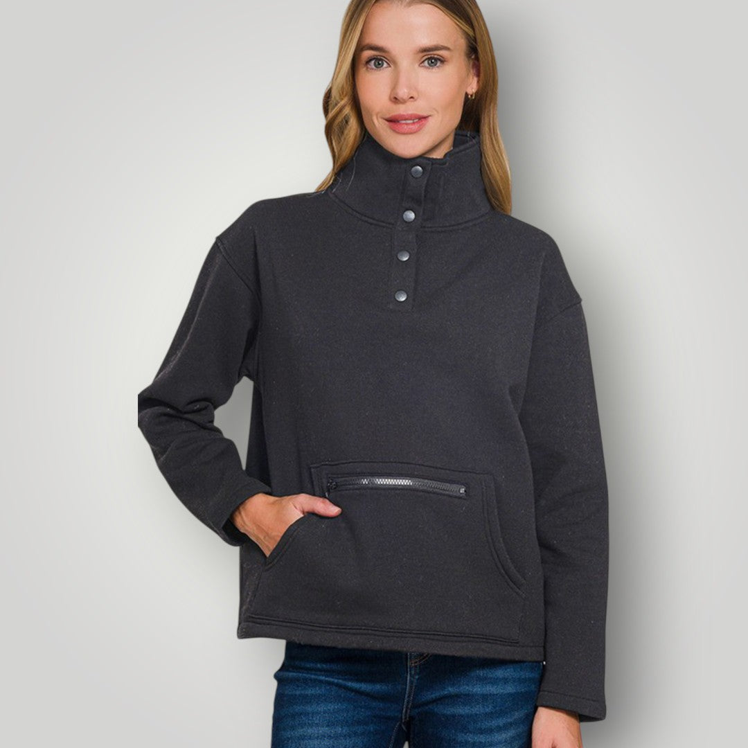Woman wearing a dark gray pullover with button details on a light gray background