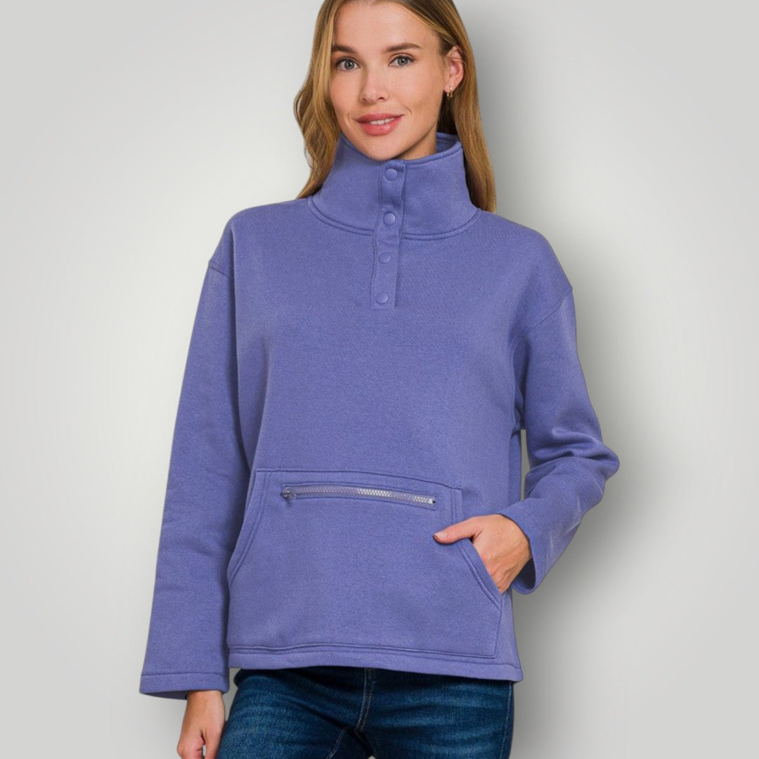 Woman wearing a blue pullover with a high collar on a plain background