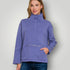 Woman wearing a blue pullover with a high collar on a plain background