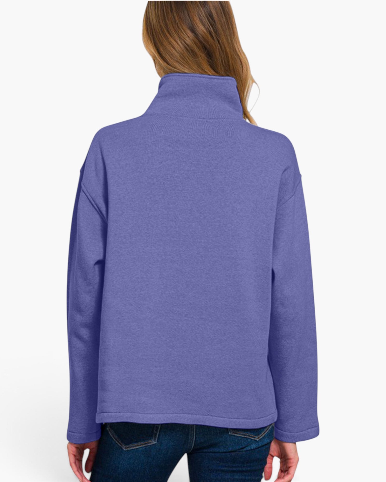 A woman viewed from the back wearing a heathered periwinkle purple quarter-zip fleece jacket and dark blue jeans, set against a plain white studio background.