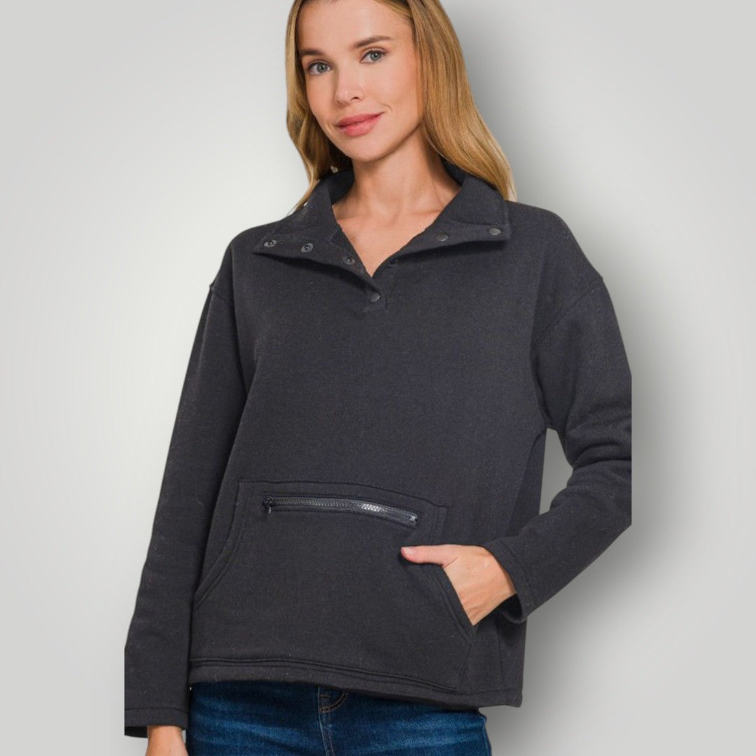 Woman wearing a dark gray pullover with a zipper pocket on a light gray background