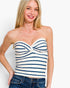 A woman wearing a strapless knit top with horizontal navy blue and off-white stripes, paired with blue jeans, against a plain white background.