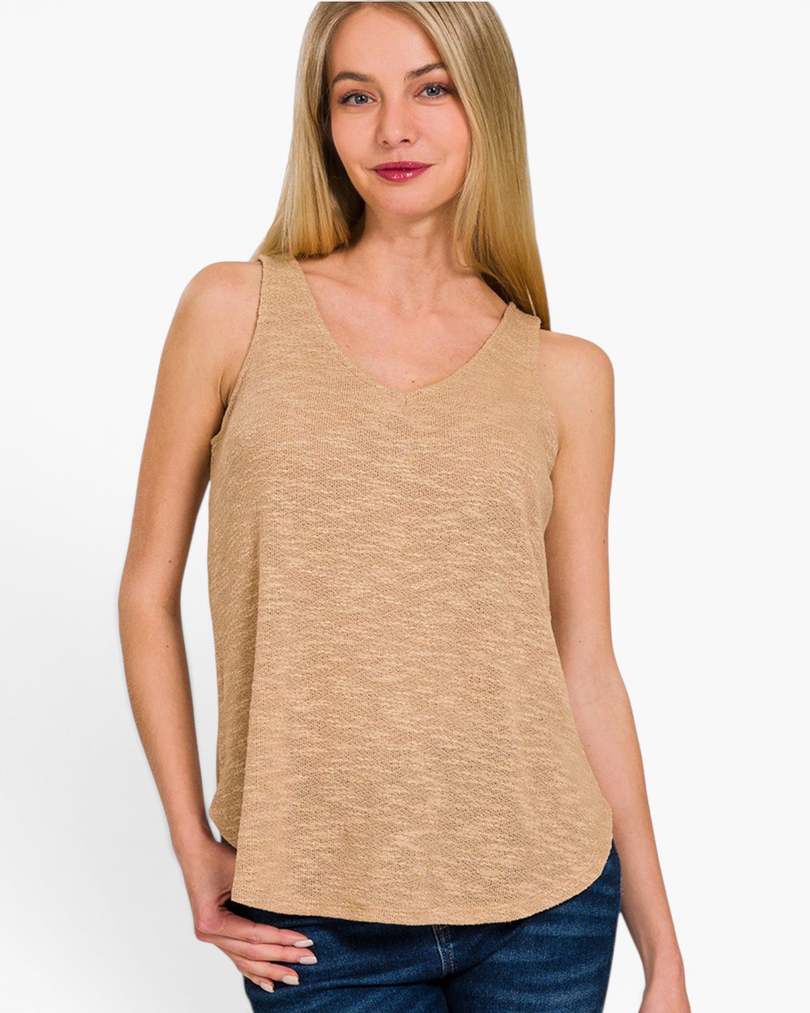 A woman wearing a sleeveless V-neck tank top in a heathered tan color, paired with blue jeans, against a plain white studio background.