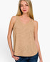 A woman wearing a sleeveless V-neck tank top in a heathered tan color, paired with blue jeans, against a plain white studio background.