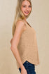 Woman wearing a beige sleeveless top against a beige background