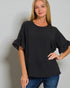 Woman wearing a black blouse with ruffled sleeves against a plain background