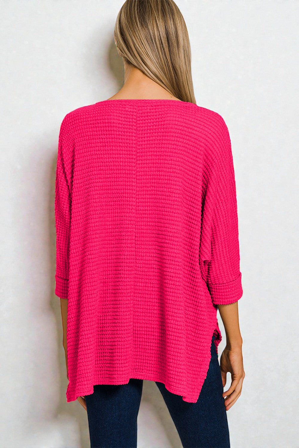Person wearing a bright pink textured sweater against a white background