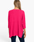 A woman viewed from the back wearing a bright pink waffle-knit long-sleeve top and dark blue jeans against a plain white background.