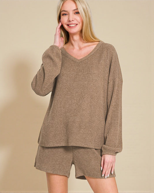 Woman wearing a brown sweater and shorts set against a beige background