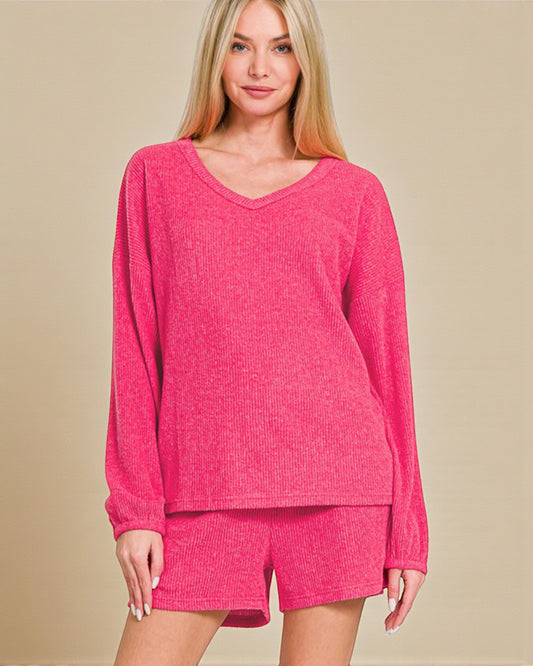 Woman wearing a pink long-sleeve top and shorts set on a beige background