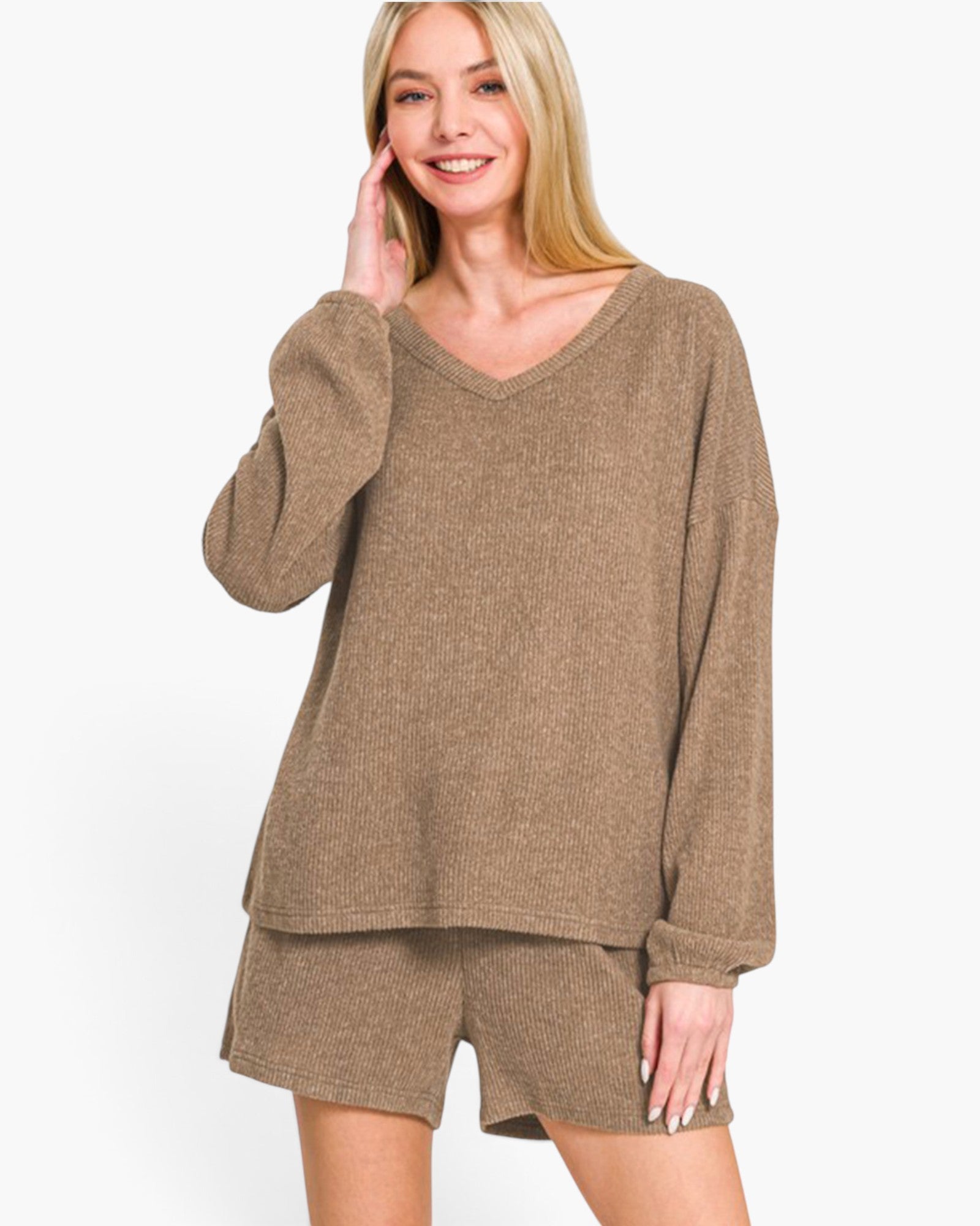A woman modeling a matching lounge set consisting of a long-sleeve V-neck knit top and coordinating shorts in a heathered taupe-brown color, set against a plain white studio background.