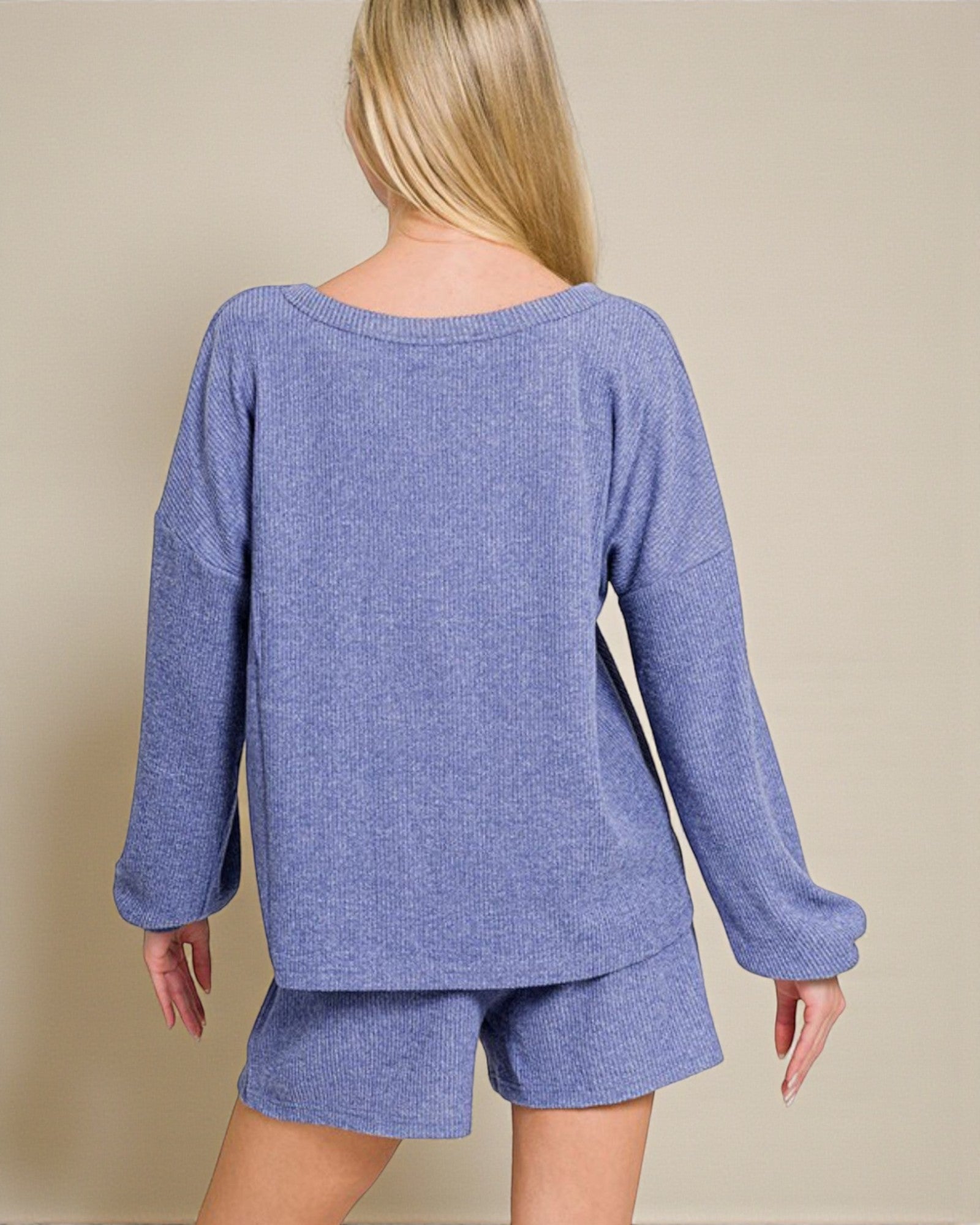 Person wearing a blue knit outfit with shorts on a beige background