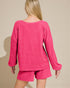 Person wearing a pink knitted outfit on a beige background