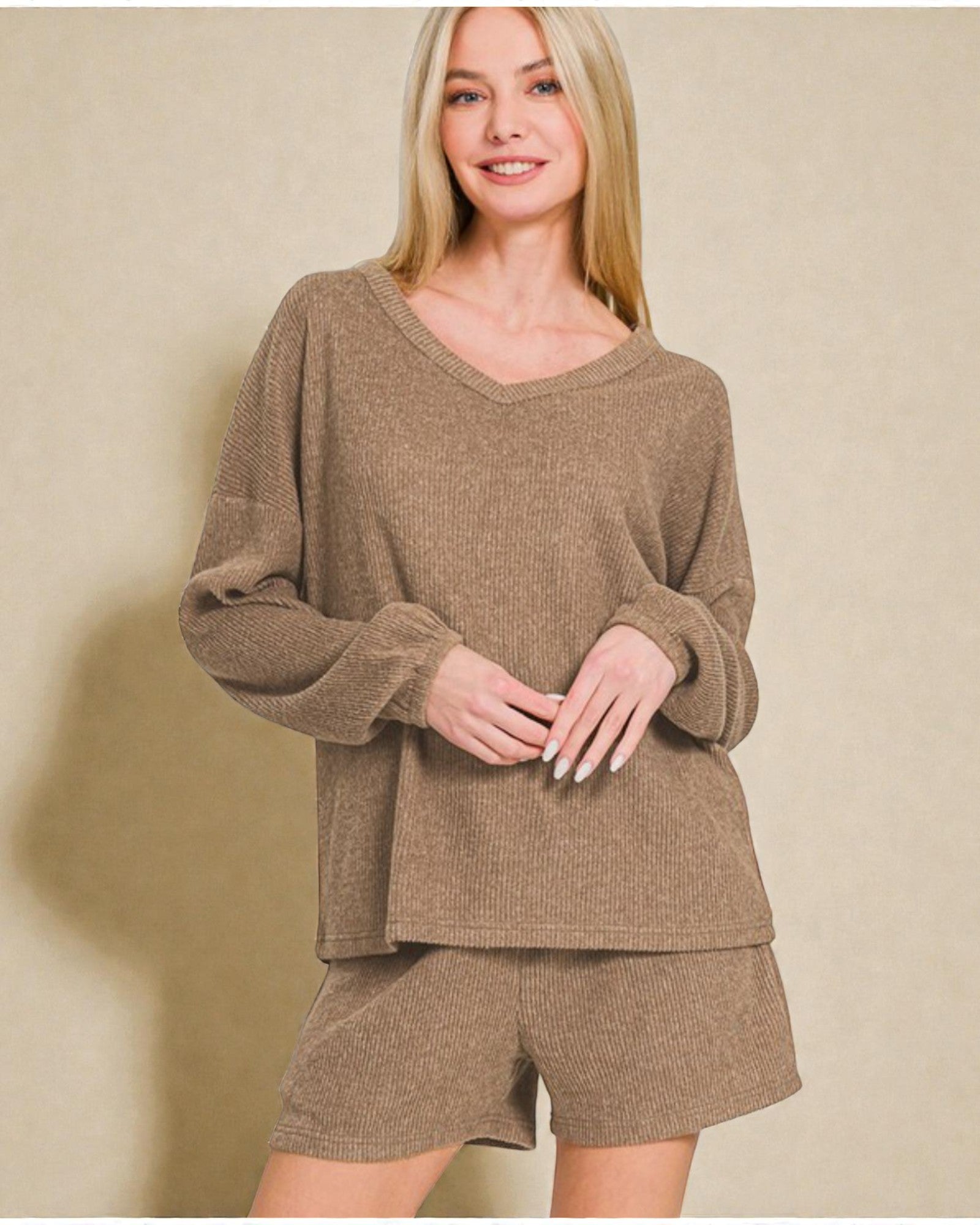 Woman wearing a brown sweater and shorts set against a beige background