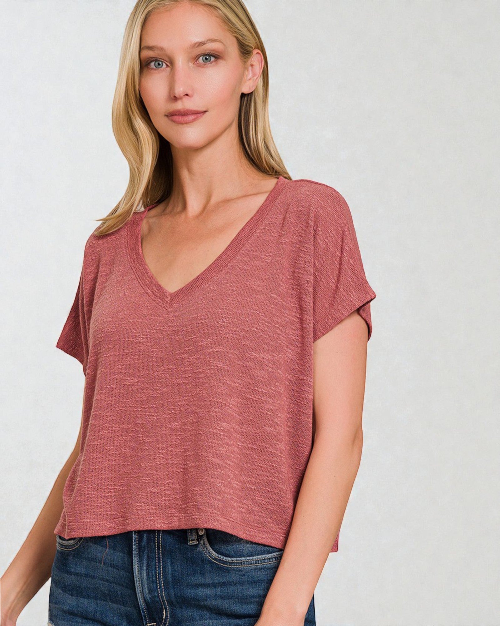 Woman wearing a maroon t-shirt and blue jeans on a white background